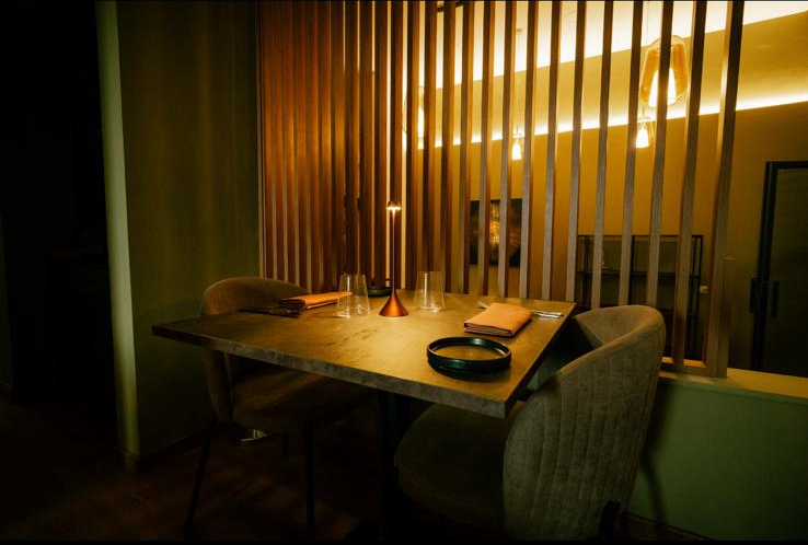 Room detail: fine wine glasses in the foreground, wood panelling and a contemporary relief sculpture